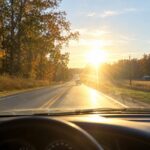 Bright low sun shining across a Mississippi road as two cars approach an intersection.